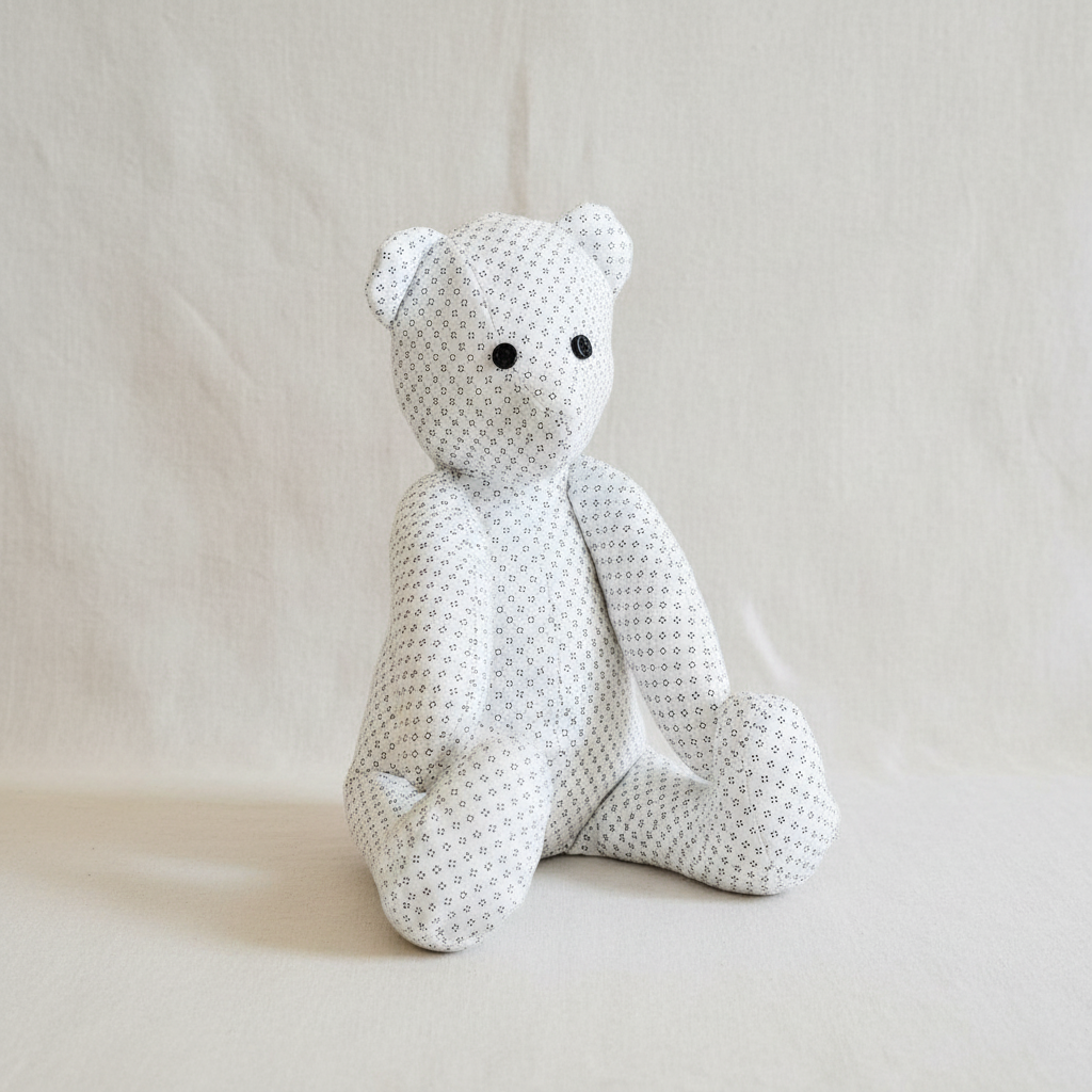 Ourson peluche fait main en tissu blanc à pois bleus, fond blanc épuré